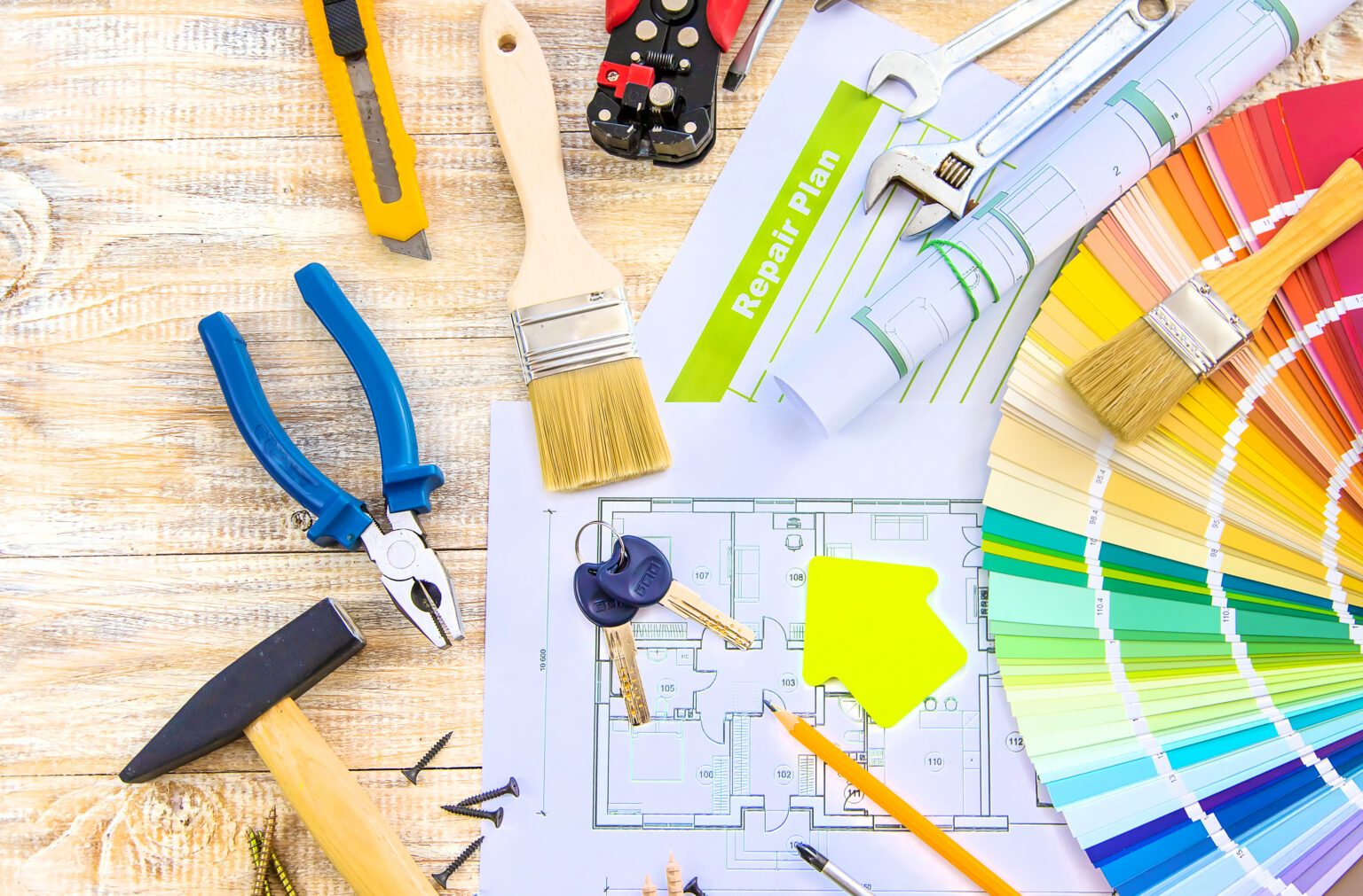 Paint palette, house plans, and remodeling tools on a workbench