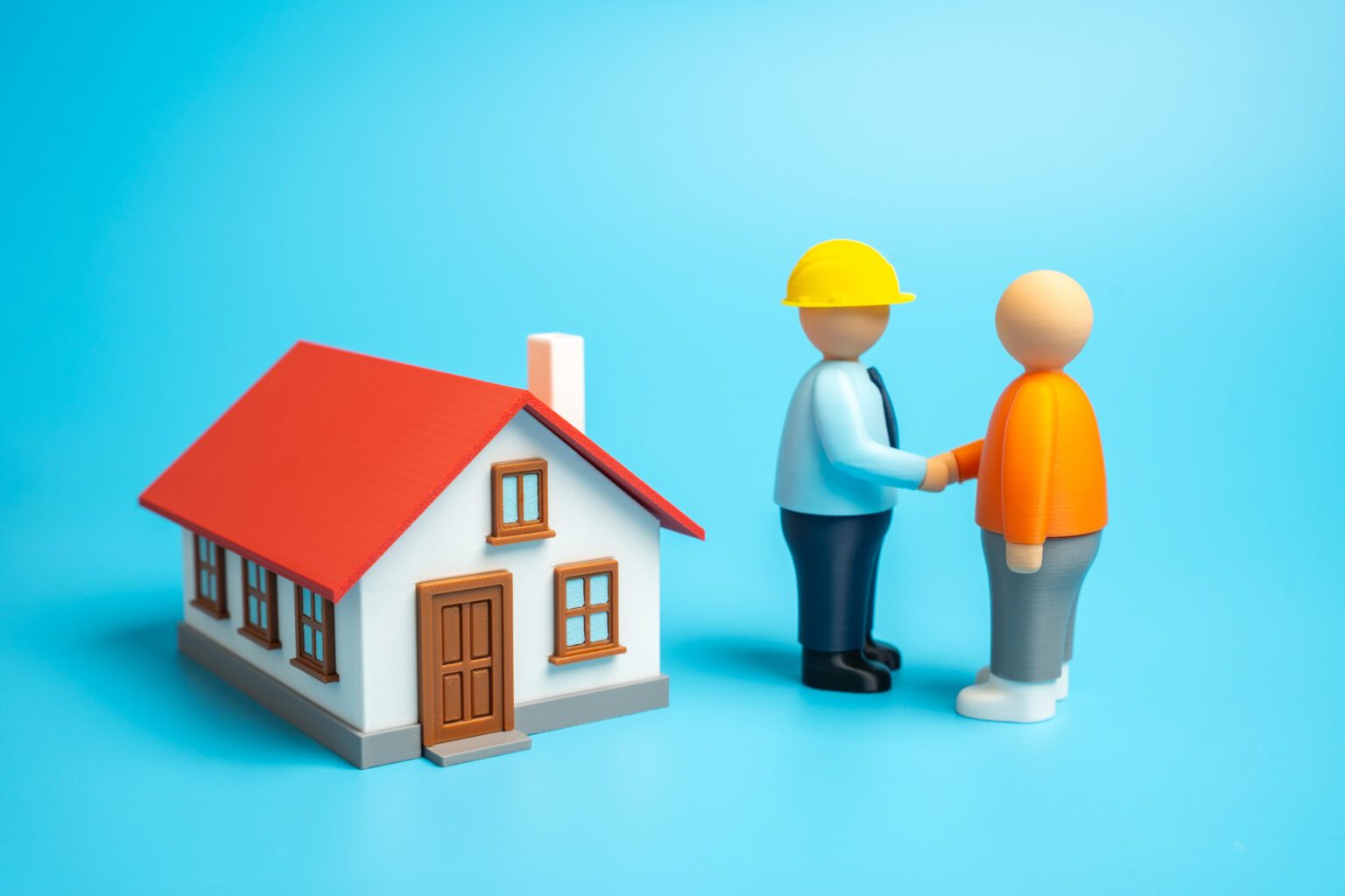 A homeowner shaking hands with a contractor over house plans